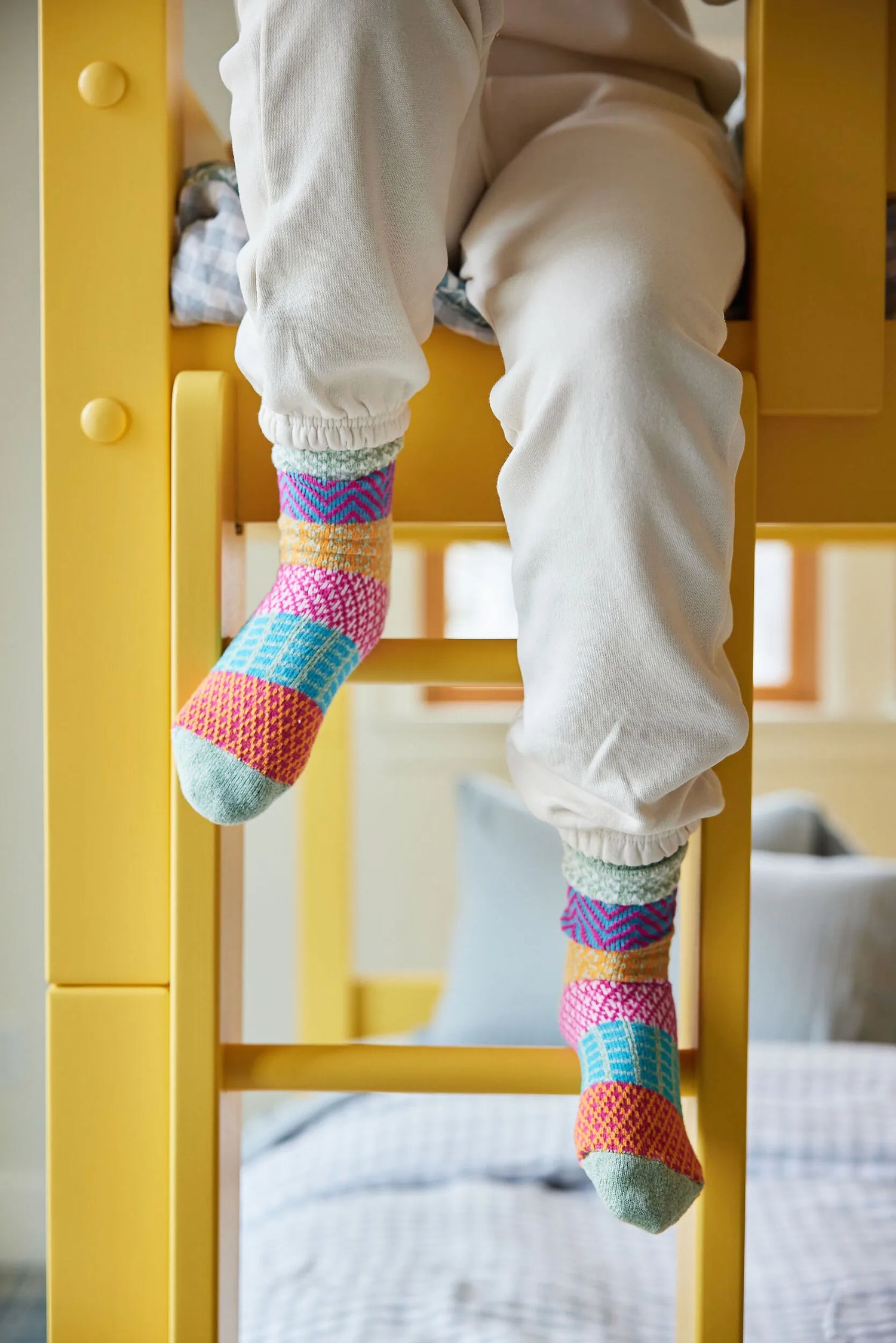 Closeup of a child walking down the ladder of a bright yellow bunk bed.