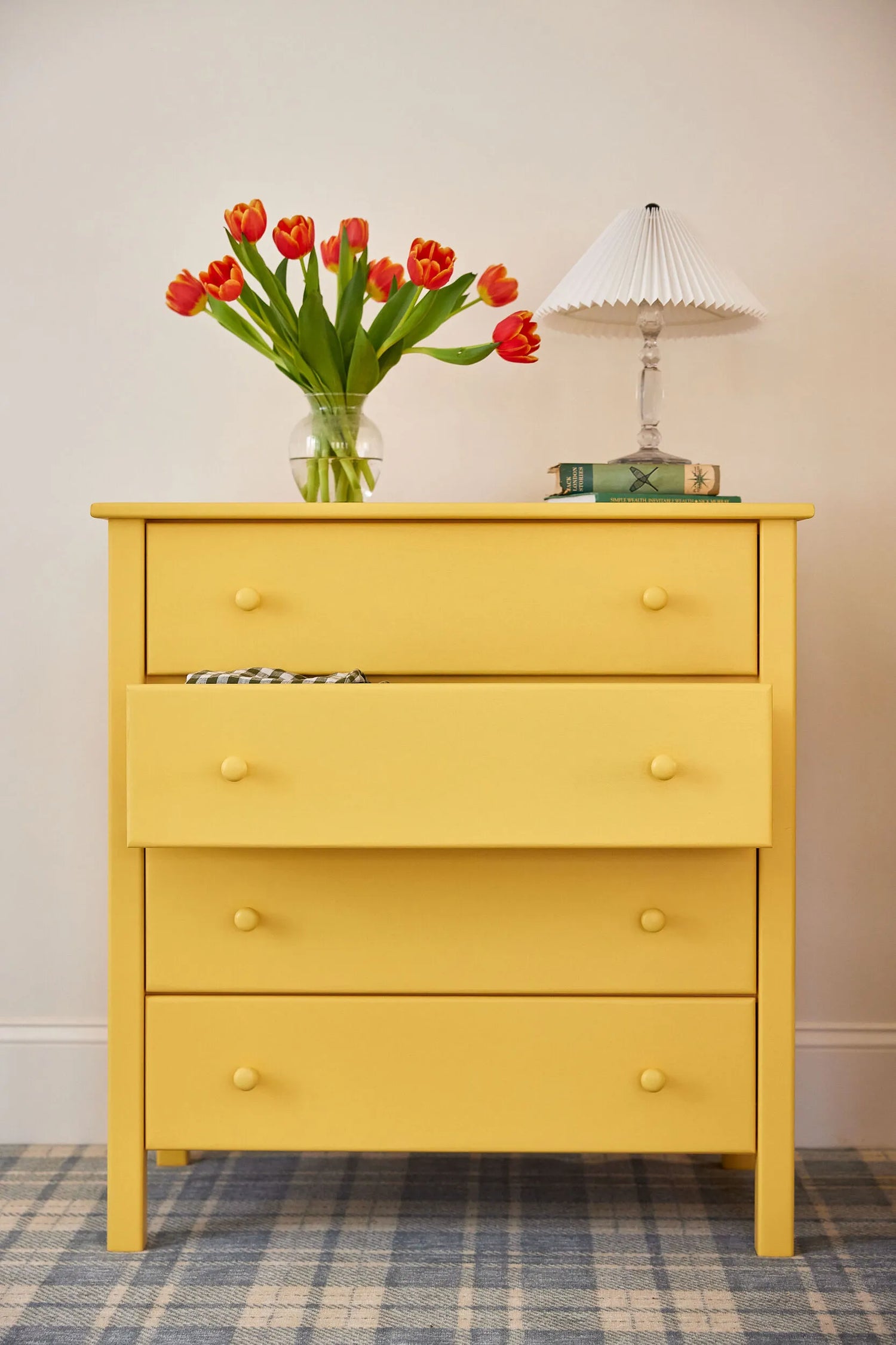 A four drawer dresser finished with a bright yellow Benjamin Moore paint.