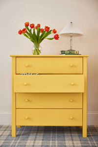 A four drawer dresser finished with a bright yellow Benjamin Moore paint.