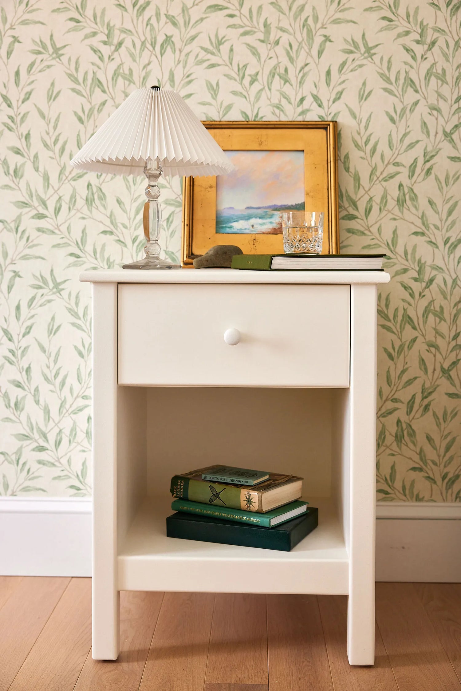 A one drawer nightstand finished with a white Benjamin Moore paint.