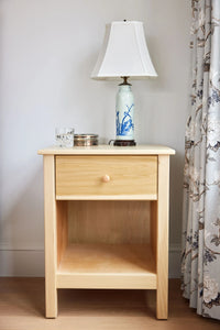 A one drawer nightstand finished in a natural wood color.