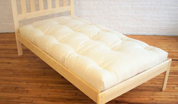 A handmade cotton and wool mattress on a simple wood platform bed.