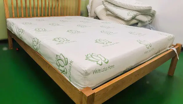 A simple mattress with a green floral decoration on a simple wood platform bed.