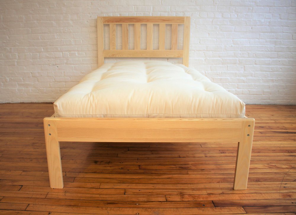 A wooden bed frame with a thick mattress on top