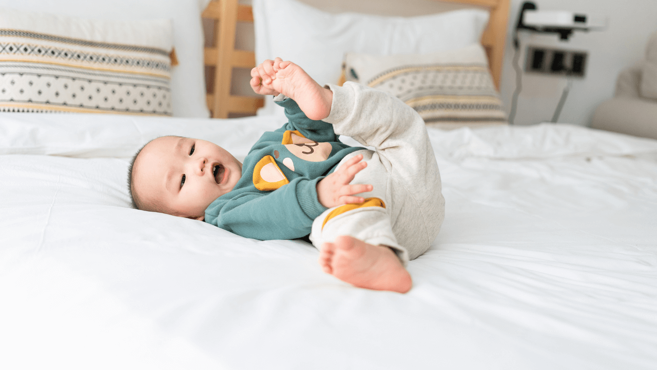 A small baby laying on a mattress