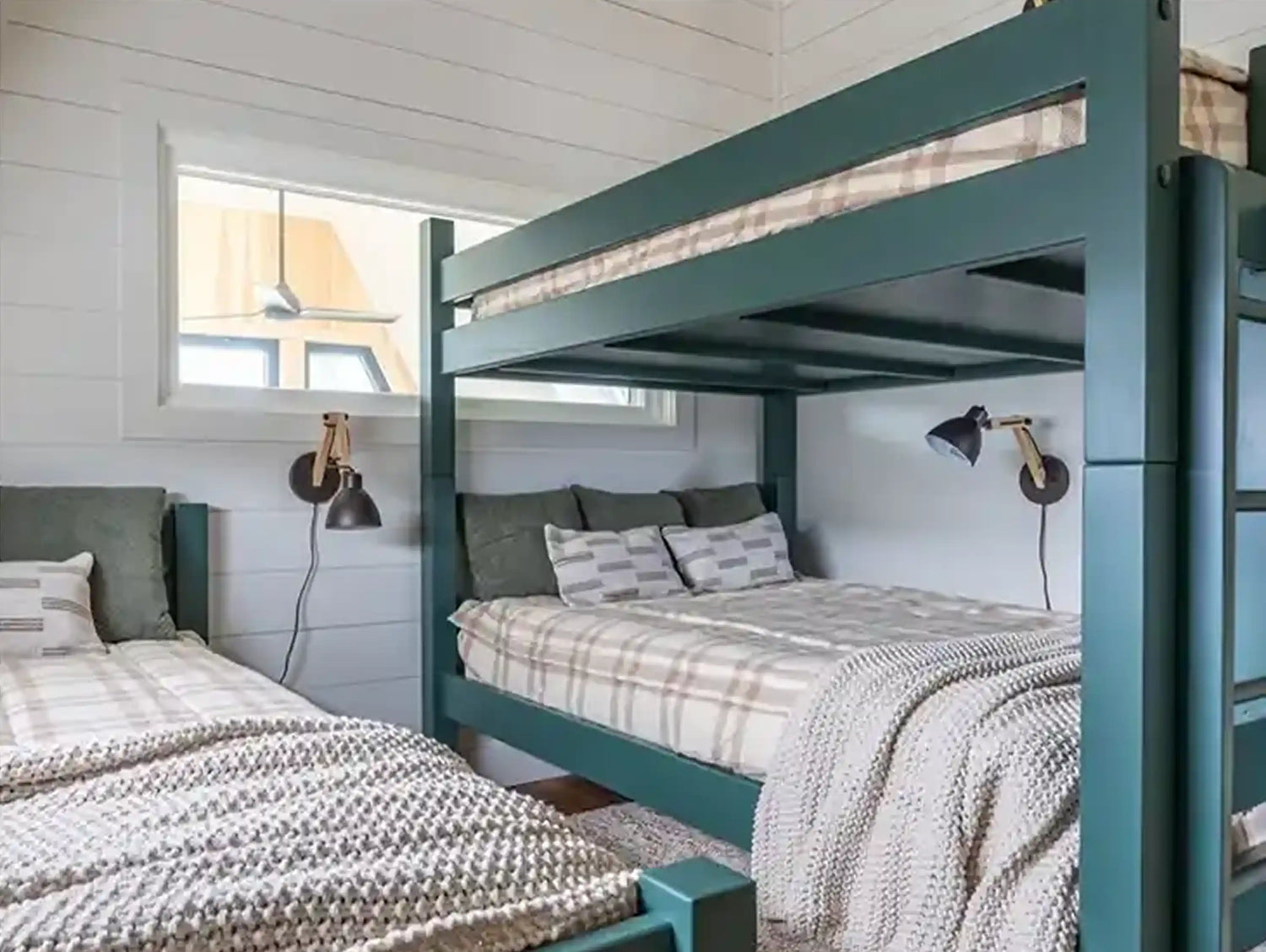 A Green twin over twin bunk bed next to a single full green camp bed